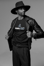 REBELLION black tee by KRASSWERK – worn by male model in monochrome fashion portrait, bold pose with open leather jacket