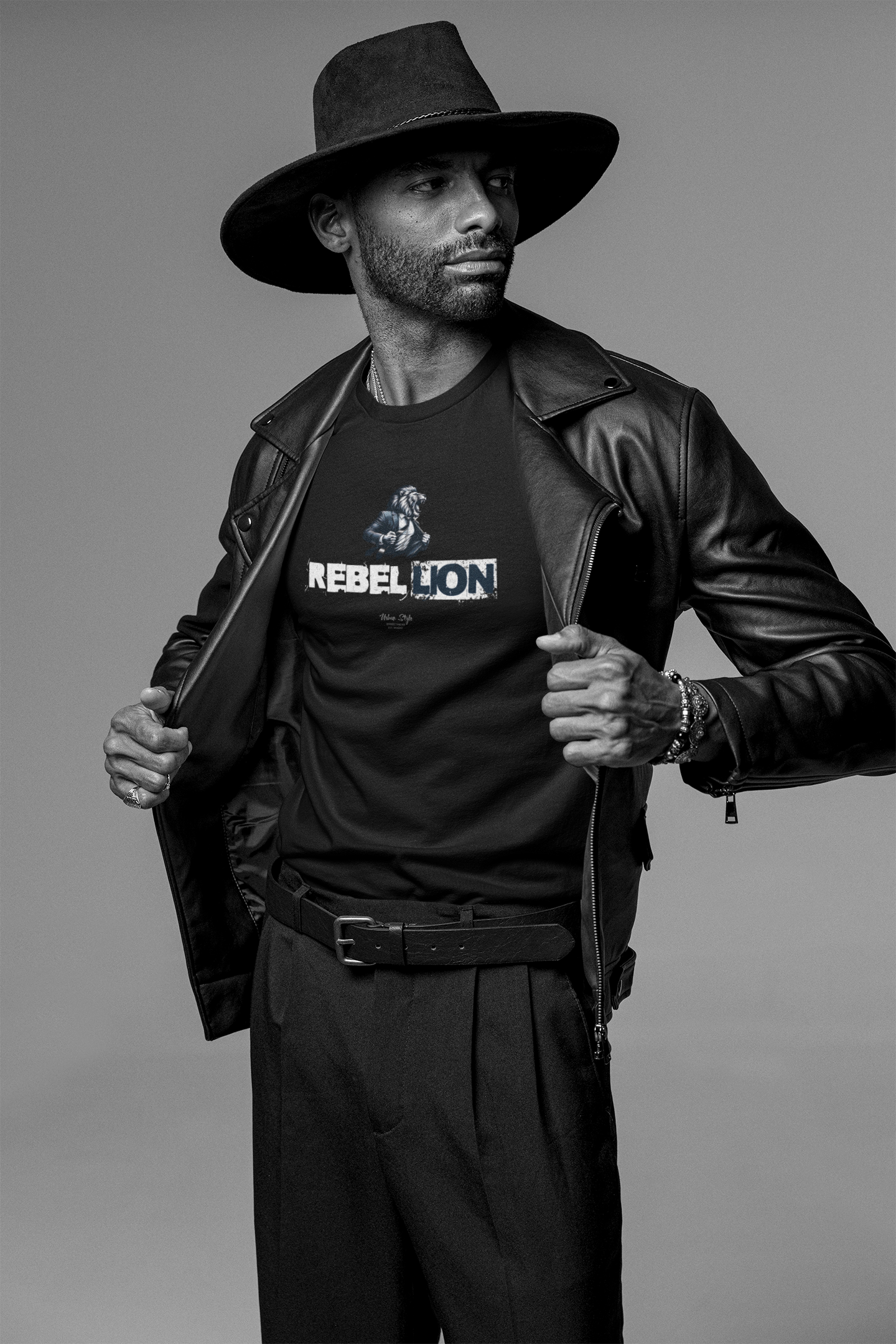 REBELLION black tee by KRASSWERK – worn by male model in monochrome fashion portrait, bold pose with open leather jacket