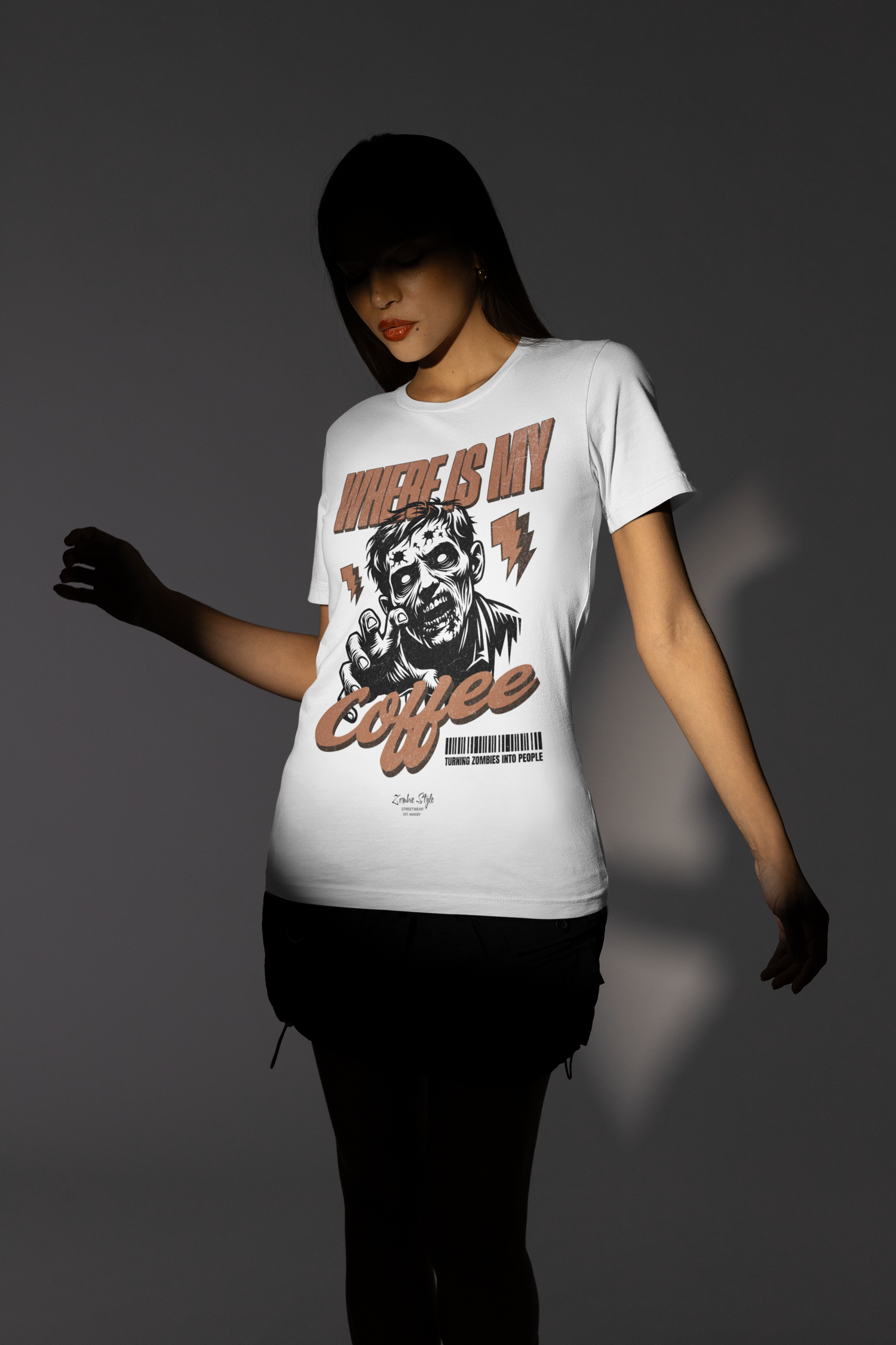 “Where Is My Coffee?” white tee by KRASSWERK – worn by female model in moody lighting, zombie artwork contrasted against soft shadows