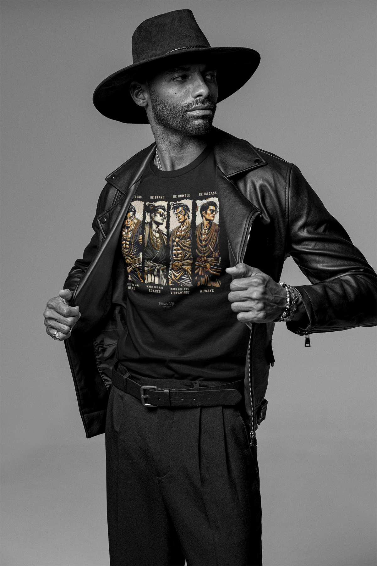 “BADASS” black tee by KRASSWERK – worn by male model in monochrome studio portrait with noir leather styling, samurai warrior artwork, and powerful stance