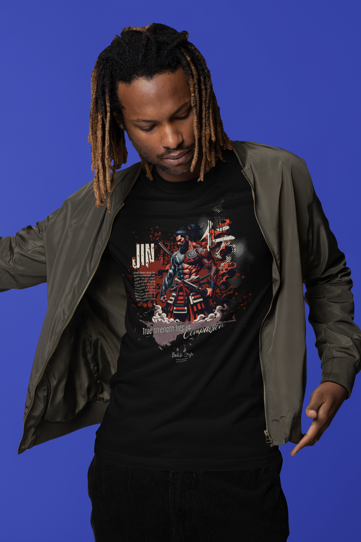 “JIN” black tee by KRASSWERK – worn by male model in streetwear jacket with blue backdrop, samurai-inspired warrior graphic symbolizing strength and compassion