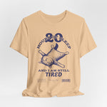 3D mockup of the “STILL TIRED” t-shirt in Sand Dune — warm beige tone with no background or model.