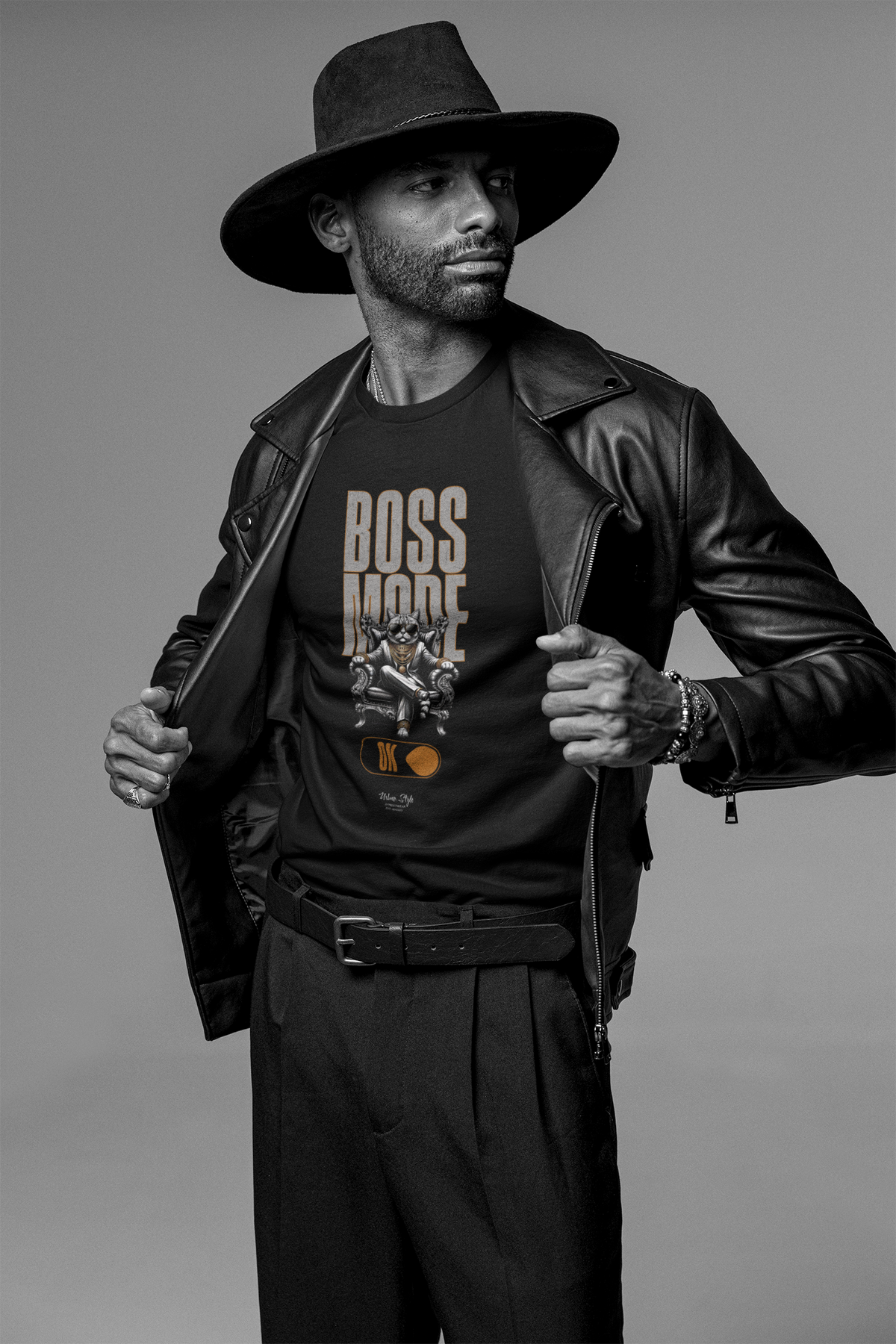 A confident male model in a black leather jacket and wide-brim hat shows off the BOSS MODE t-shirt. The design features a throne-sitting figure above the words “BOSS MODE” with a glowing switch.