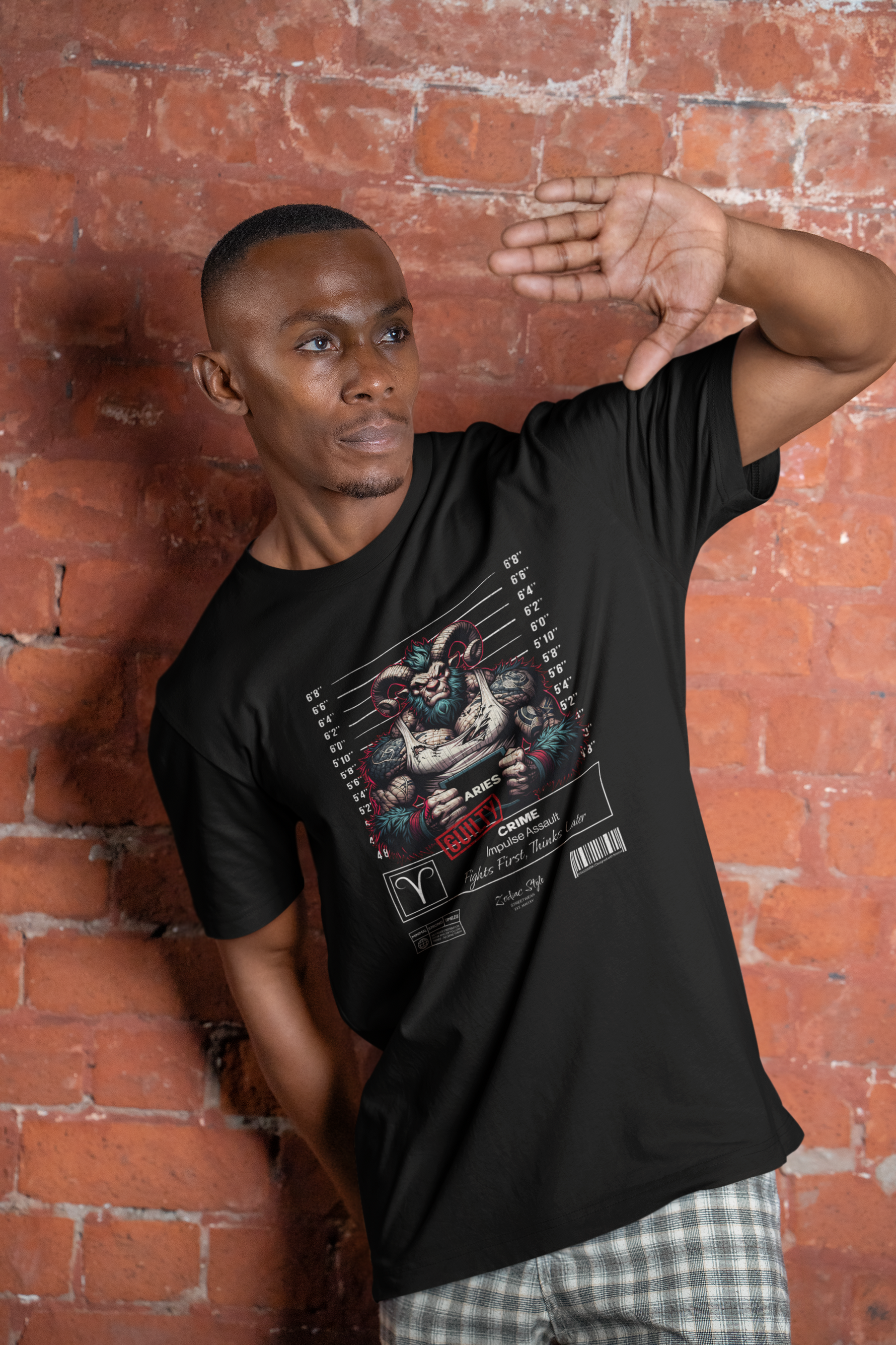 A man poses against a brick wall wearing the "ARIES – GUILTY" tee featuring a muscular ram in a mugshot. The phrase “Fights First. Thinks Later” stands out beneath.