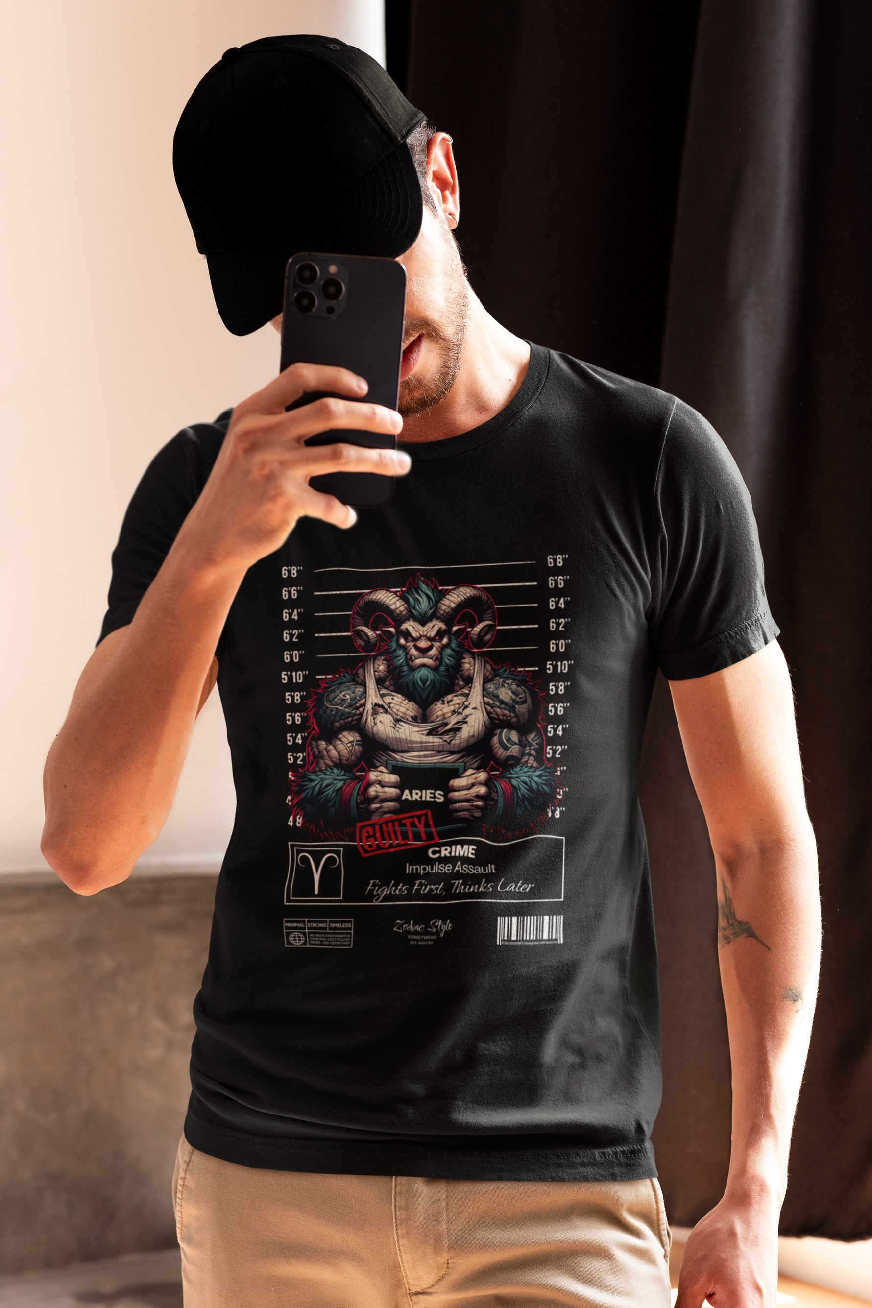 Man covering face with phone while wearing the ARIES tee — edgy design featuring a guilty ram in a mugshot scene.