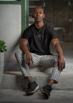 Man wearing a black t-shirt with a logo, sitting on a concrete surface.