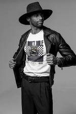 Man in black hat and leather jacket revealing a white graphic tee with a throne-sitting cartoon cat. The shirt reads "I DON'T RULE. I COMMAND." with a bold checkered backdrop.