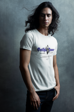 Model stands with flowing hair against a moody grey backdrop, wearing the "Gothic Power" t-shirt in white. The purple gothic text and skull design evoke ancient strength and dark elegance.