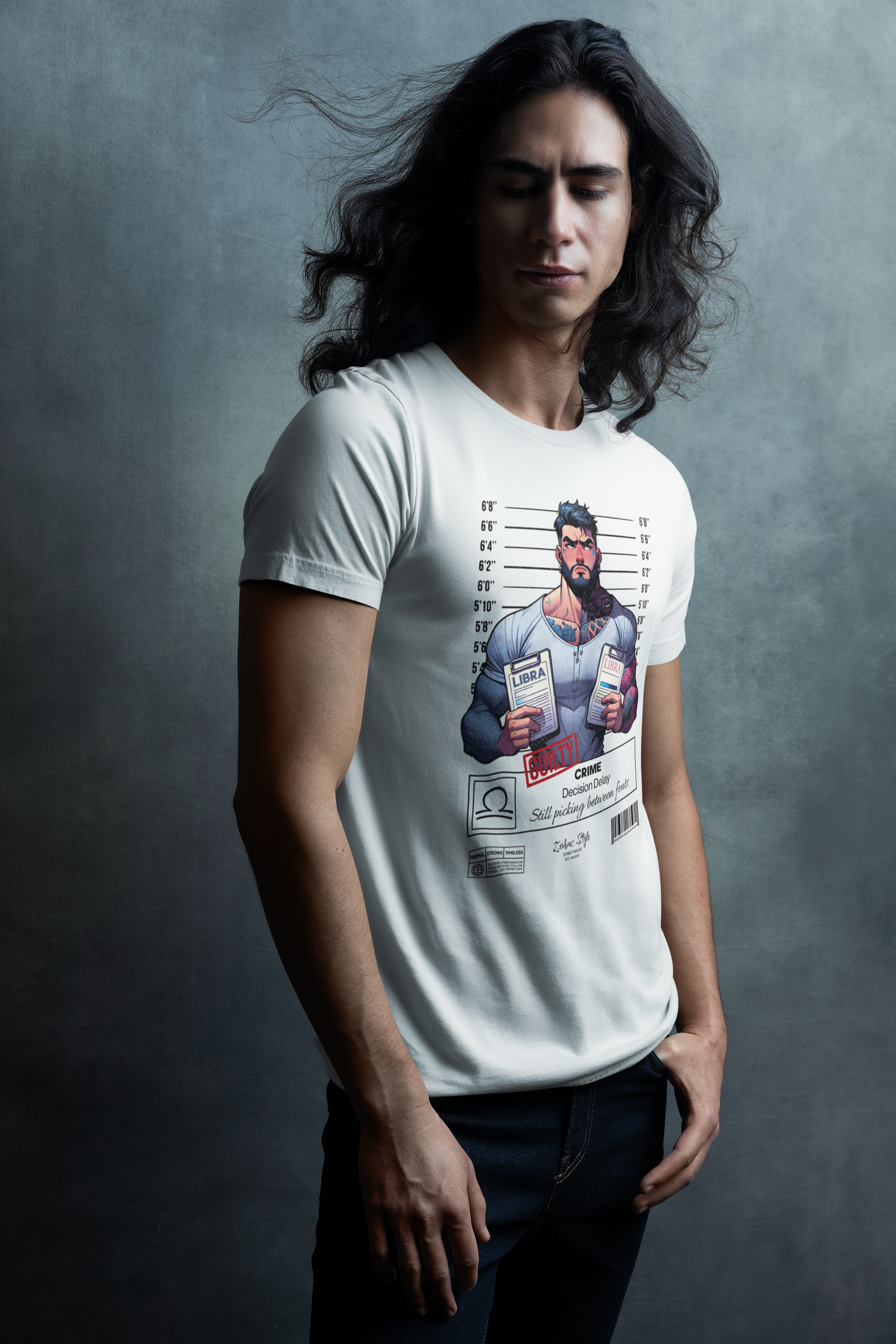 Man standing against a dark textured backdrop, wearing the LIBRA t-shirt in white. Shirt design features a muscular man holding two folders marked LIBRA, with crime description: Decision Delay. Model’s long hair adds dramatic flair to the moody studio setting.