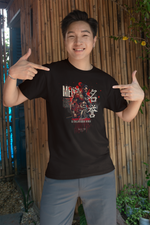 “MEIYO” black t-shirt by KRASSWERK – lifestyle photo of smiling man in casual shorts, pointing proudly at honor-themed samurai design in a tropical outdoor setting