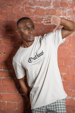 A stylish man opens his leather jacket to reveal a bold "Outlaw – Make Your Own Path" white T-shirt, channeling a modern cowboy vibe with confidence and edge.