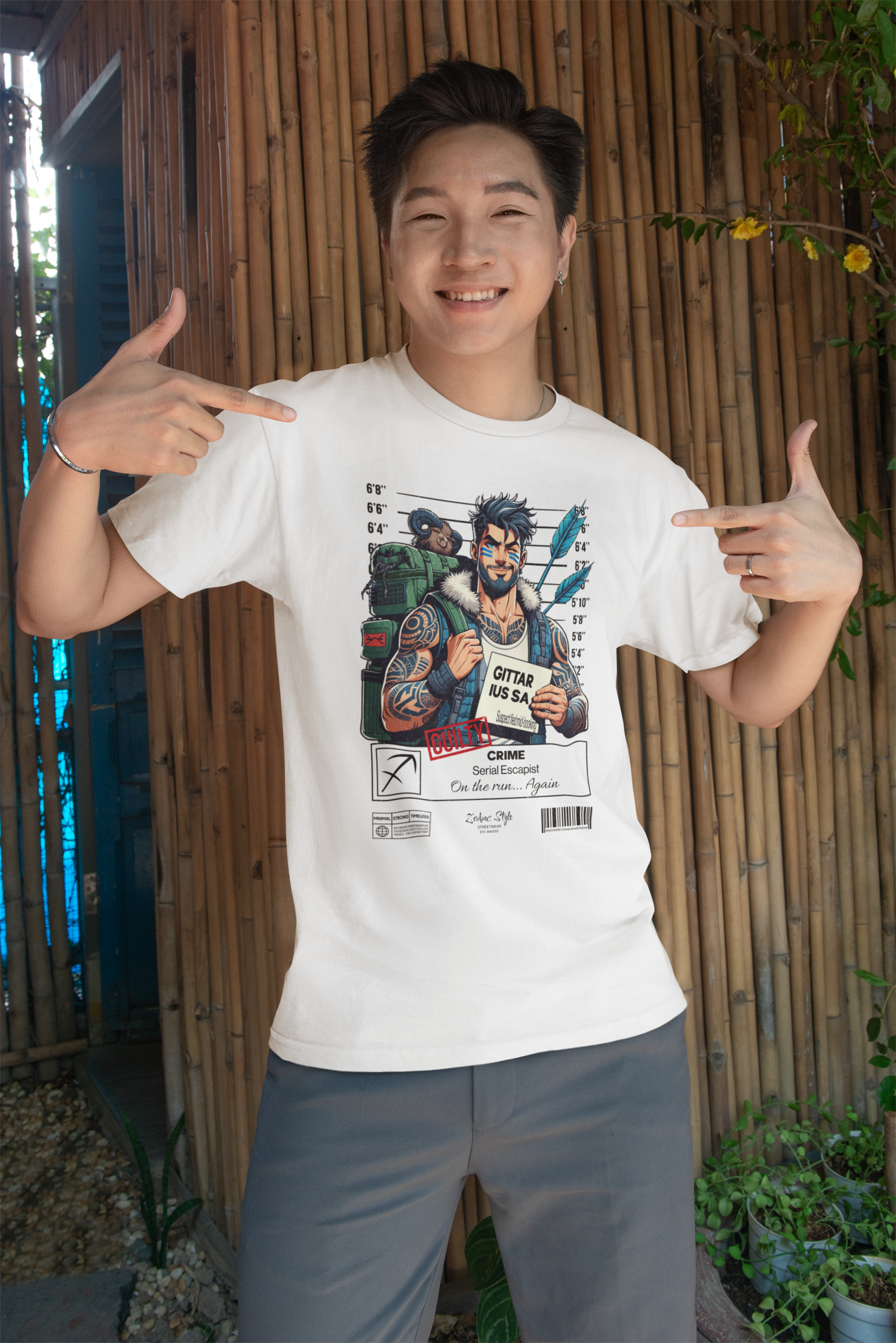 White t-shirt worn by a smiling man standing in front of a bamboo wall. He points at the shirt design, which features a rugged archer-themed character with a feathered arrow, backpack, and raccoon companion in a mugshot lineup. Caption: 'Serial Escapist – On the run… Again.'