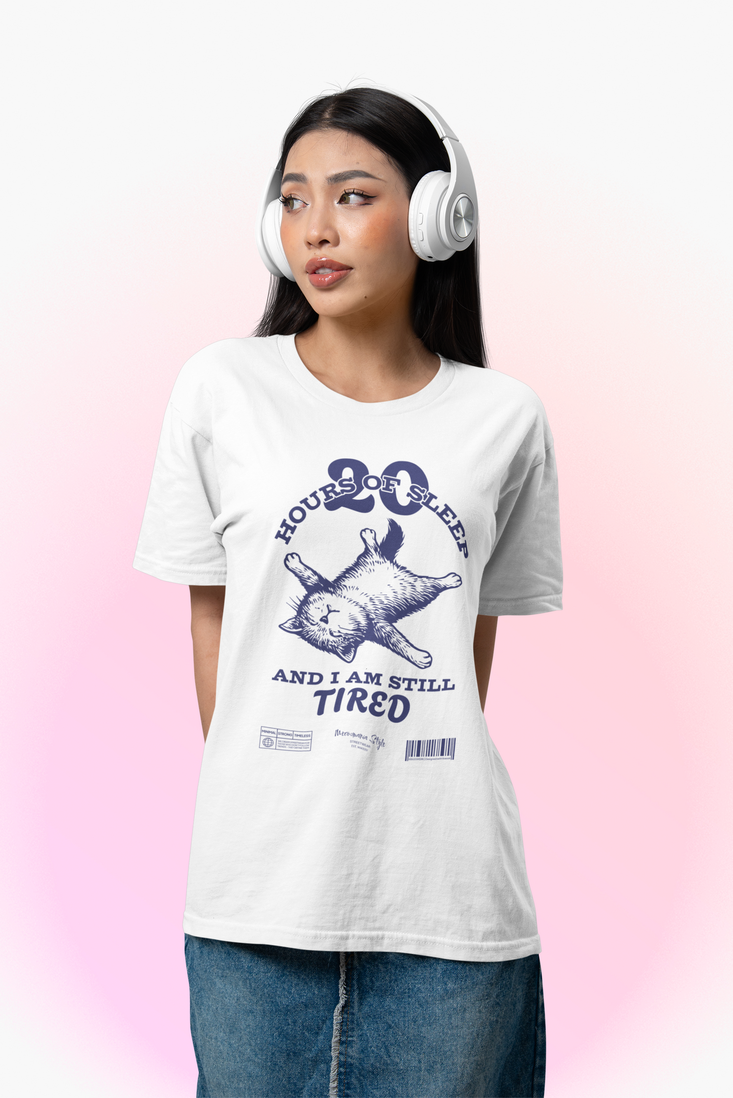 Young woman in headphones looks to the side while wearing a white t-shirt with a relaxed cat design. The shirt reads: “20 HOURS OF SLEEP AND I AM STILL TIRED.”