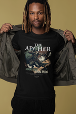 A confident man smiling in a studio setting, opening his jacket to reveal THE ARCHER t-shirt design featuring a crouched archer mid-draw and the slogan “Strike True. Strike Silent.” A warm beige background adds contrast to the dark tee and highlights the character’s focused stance.