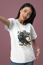 A confident woman smiling playfully while taking a selfie, wearing THE ARCHER t-shirt in white. The design features a hooded archer mid-draw with the slogan “Strike True. Strike Silent.” A soft rose background adds a fresh, modern touch that contrasts the bold artwork.