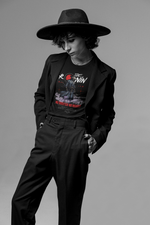 Model wears The Ronin t-shirt under a wide-brim hat and blazer — calm pose reflects the shirt’s lone warrior theme.