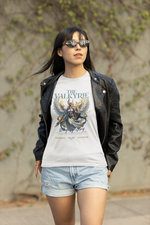 A confident female model walks outdoors in sunglasses and a black leather jacket, wearing THE VALKYRIE t-shirt. The design shows a celestial warrior with radiant wings and the phrase “Wings of Glory.”