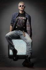 A bold man in sunglasses sits on a static-filled retro TV, wearing THE VIKING t-shirt featuring a roaring Norse warrior and the slogan “Raise The Storm”.